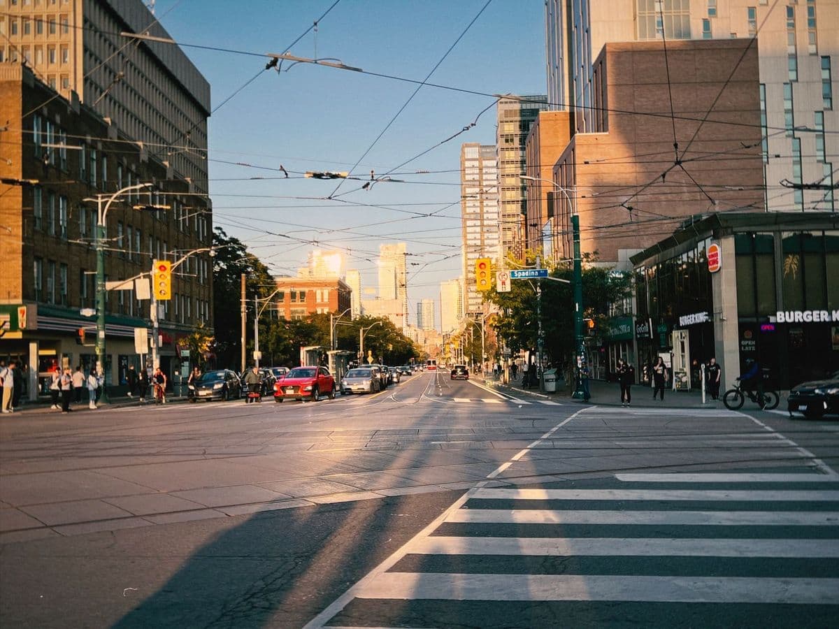 Bustling city street intersection with overhead lines and traffic at sunset.